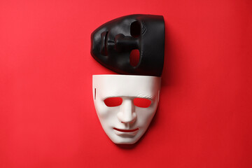Theater arts. White and black masks on red background, top view