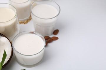 Different types of vegan milk and ingredients on white table, closeup. Space for text