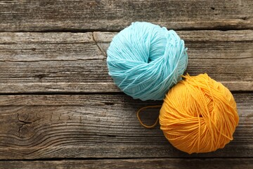 Two colorful yarns on wooden table, flat lay. Space for text