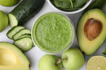 Tasty green smoothie in glass and products on white tiled table, flat lay