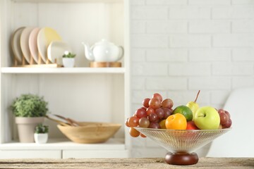 Glass vase with different fresh fruits on wooden table. Space for text