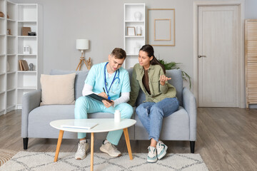 Obraz premium Male doctor listening to ill young woman at home