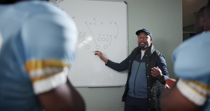Black man, football coach and whiteboard with team for game plan, strategy or discussion on formation in locker room. African mentor or sports trainer talking to group for presentation on match ideas