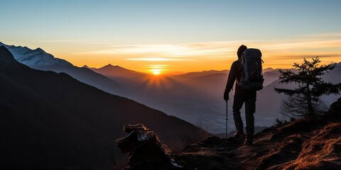 Silhouette of hiker enjoying sunrise on top of a mountain. Concept for conquering adversity, achieving goals, and adventure travel.