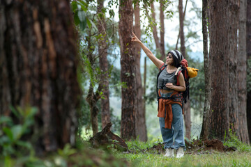 Asian female backpacker with binocular watch nature scenery and birds, point out something in the...