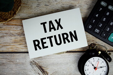 Tax Return text with alarm clock and calculator on wooden background, Business concept