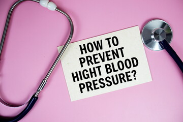 How to prevent higt blood pressure? text on paper card with stethoscope top view on pink background