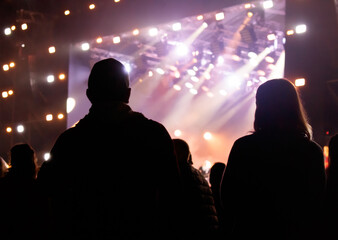 Silhouettes of spectators against the background of light at a concert