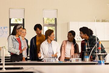 In high school laboratory, students listening to teacher explaining science experiment