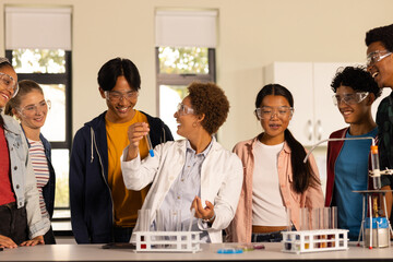 Wearing safety goggles, students conducting science experiment in high school classroom