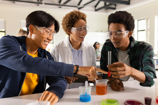 In high school, teenagers conducting science experiment with test tubes in classroom - Powered by Adobe
