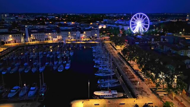 Approaching aerial movement to the Vieux Port with Grande roue at night, La Rochelle, France.