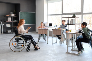 Mature teacher in wheelchair conducting lesson at school