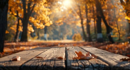 Wooden table with autumn leaves and sunlight in the background