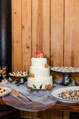 Wedding cake with dried orange slices and florals on a dessert table.