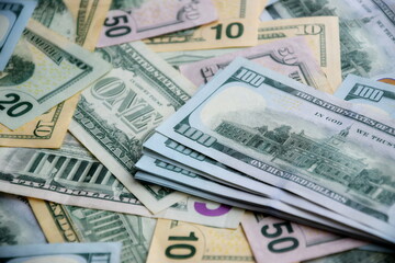 Big amount of US dollar bills in different nominations on table. Many dollar banknotes under natural light