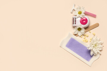 Modern epilator with razor, wax strip and flowers on beige background