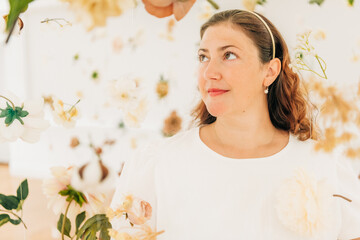 Woman surrounded by white and soft-colored flowers, looking serene