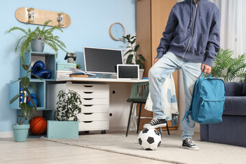 Teenage boy with soccer ball and backpack at home