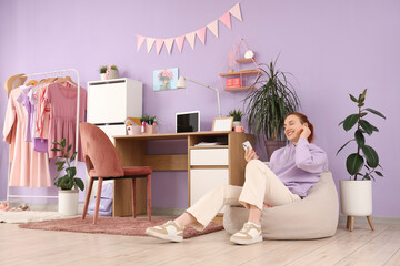 Teenage girl in earphones with mobile phone listening to music at home