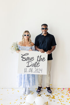 Couple holding a "Save the Date" sign with wedding date