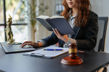 A bespectacled lawyer or legal consultant working at the level of justice sits at a table and holds a pen to view information. Detailed content about jurisprudence to study in the field of law.