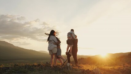 Happy family hugging in the mountains at sunset during summer vacation.