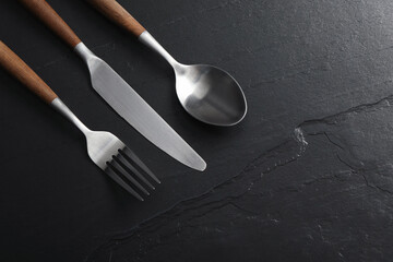 Stylish cutlery on black table, flat lay. Space for text