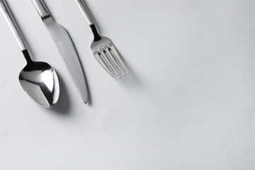 Stylish silver cutlery on white background, flat lay. Space for text