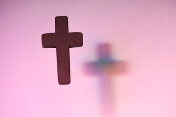 Wooden cross on pink textured background, space for text. Religion of Christianity