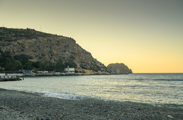 a large granite rock lies in the sea near the shore