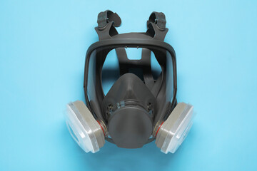 One full face respirator on light blue background, top view