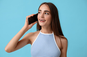 Young woman with diastema talking by mobile phone on blue background