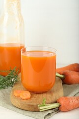 Fresh carrot juice and vegetables on light table