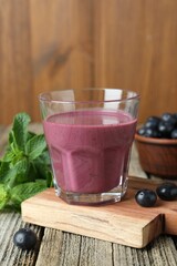 Tasty fresh acai juice in glass with berries and mint on wooden table