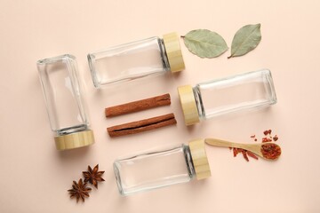 Different spices and glass jars on beige background, flat lay