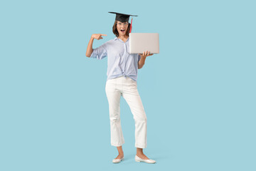 Female graduating student with laptop on blue background