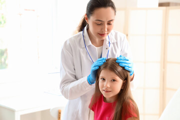 Female doctor checking little girl's head for pediculosis in clinic