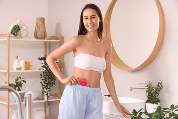 Young woman with condom in bathroom