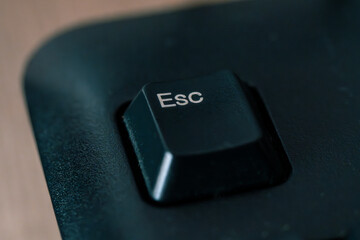 A close-up shot of the "Esc" (Escape) key on a black computer keyboard, showing the texture and detail
