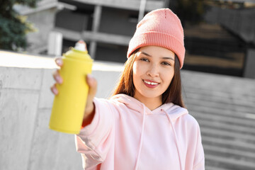 Young Asian woman with spray paint can on street, closeup