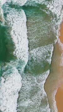 Phuket Thailand tropical beach Aerial drone top down view bird eye view of sea blue waves break on sand. Beautiful of sea water wave rip current reverse current undertow drone filming 4k vertical.