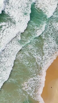 Phuket Thailand tropical beach Aerial drone top down view bird eye view of sea blue waves break on sand. Beautiful of sea water wave rip current reverse current undertow drone filming 4k vertical.