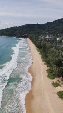 Scenic Nai Thon beach on Phuket island with waves, 4k vertical aerial video footage from drone