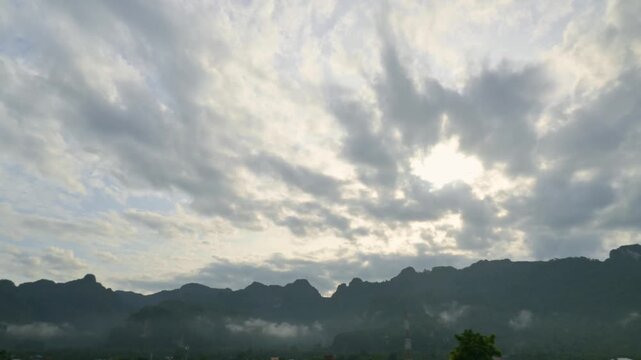 Fast motion of cloudy blue sky over mountains range. Timelapse dramatic cloudscape above the mountain with moning fog. Beautiful mist valley under amazing clouds during sunrise.