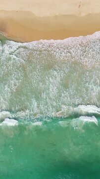 Phuket Thailand tropical beach Aerial drone top down view bird eye view of sea blue waves break on sand. Beautiful of sea water wave rip current reverse current undertow drone filming 4k vertical.