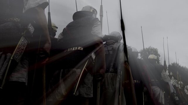 Soldiers in historical costumes reenact a march in foggy weather, creating a dramatic scene