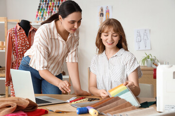 Fototapeta premium Female tailors working with fabric samples at table in atelier