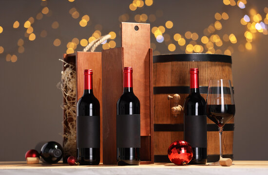 Bottles of wine, glass, wooden gift boxes, barrel corks and red Christmas balls on table