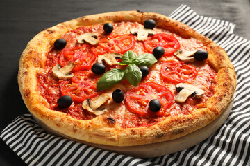 Delicious pizza with tomatoes, mushrooms, olives and basil on black table, closeup